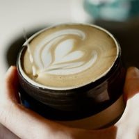 Barista giesst Milchschaum in eine Tasse mit Latte Art