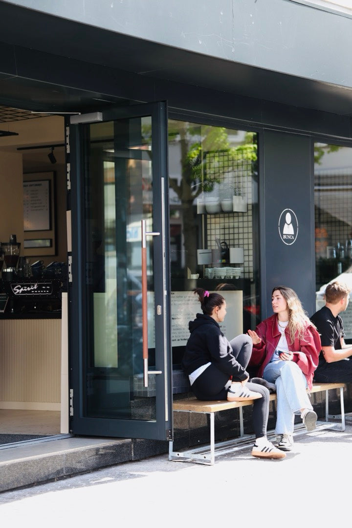Gäste sitzen auf der Bank vor dem geöffneten BUNCA. Nordend an der Berger Straße