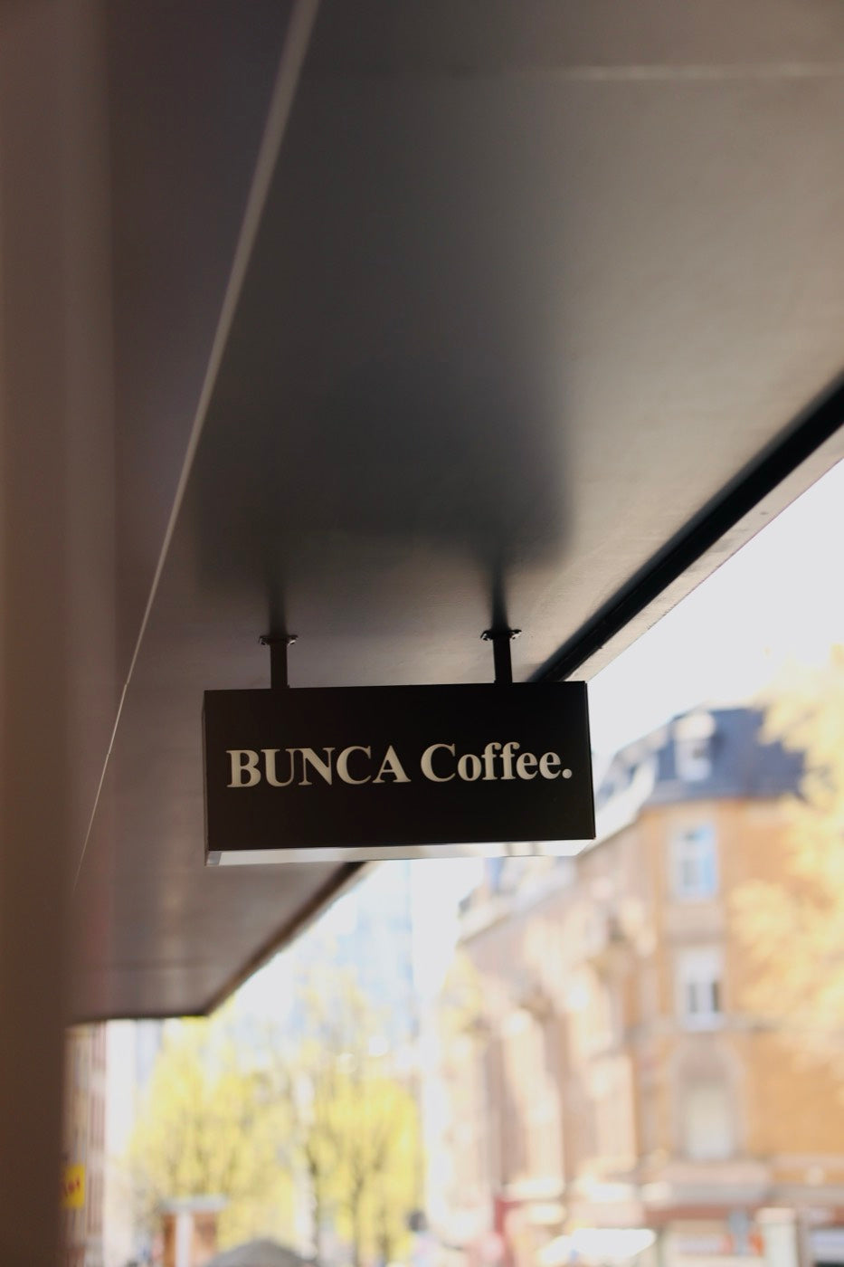 Das beleuchtete Schild BUNCA. Coffee ragt über den Gehweg der Berger Straße