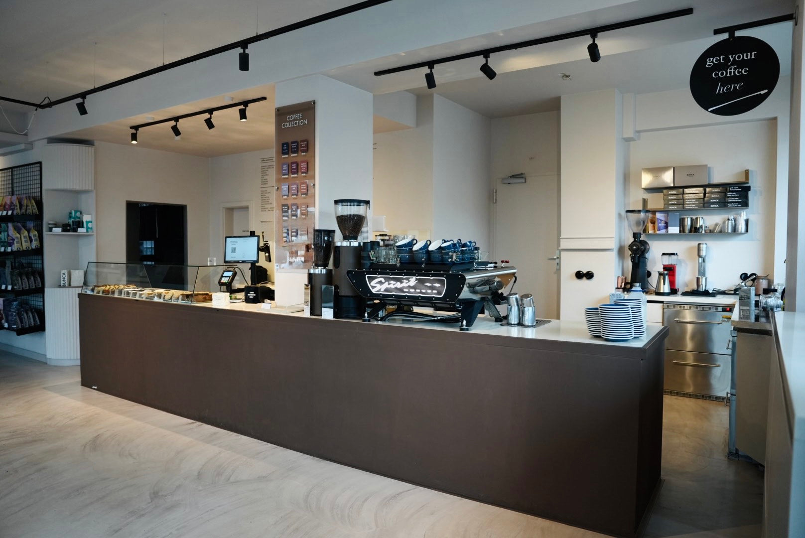 Der lange Tresen mit Siebträgermaschine, Kuchentheke und der Coffee Collection an der Wand
