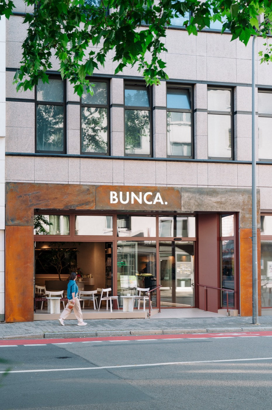 Eingang des BUNCA. Westend am Grüneburgweg, Passantin vor der geöffneten Fensterfront
